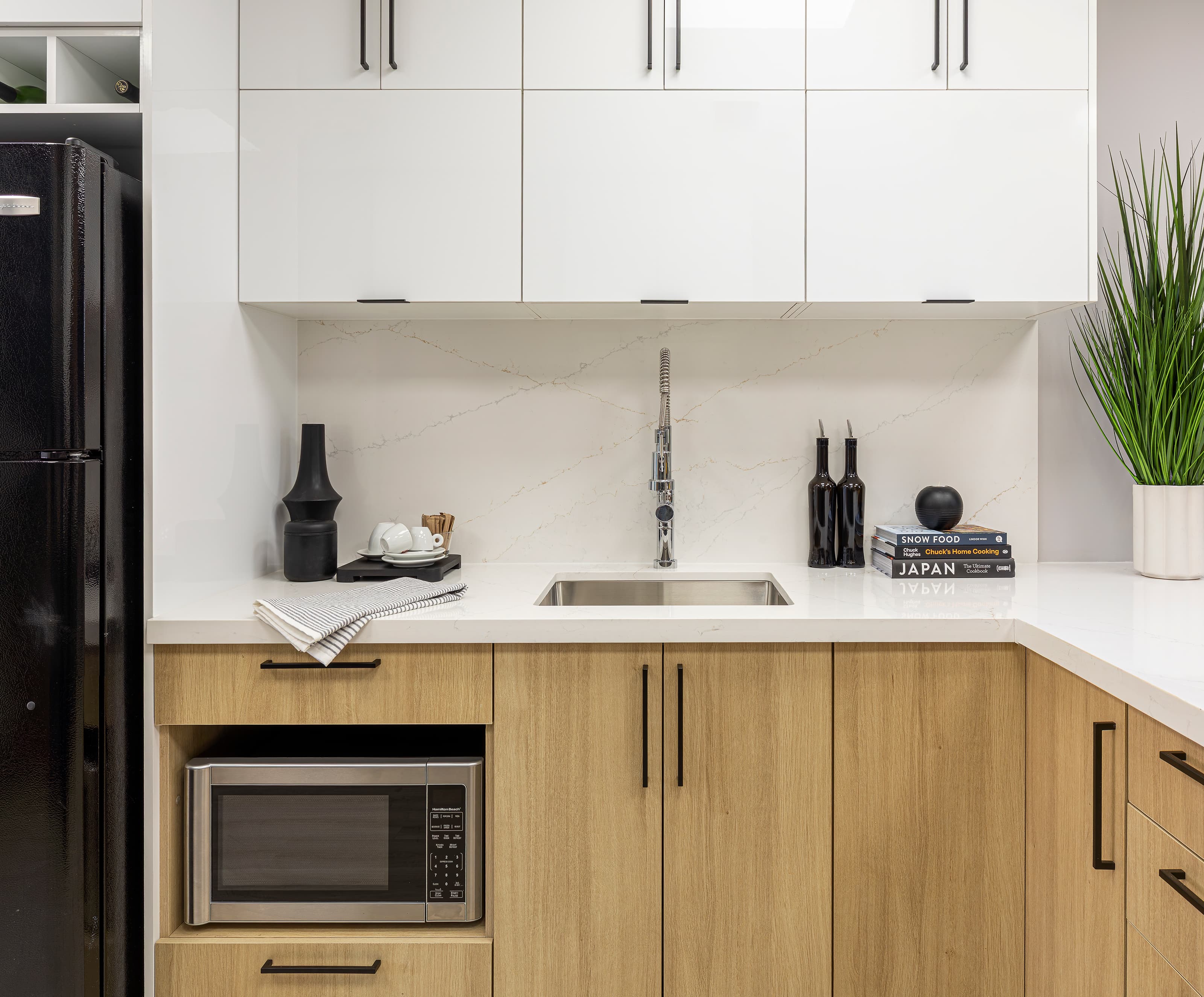 Modern two-tone kitchen with white gloss upper cabinets, wood grain lower cabinets, quartz countertop, and stainless steel faucet