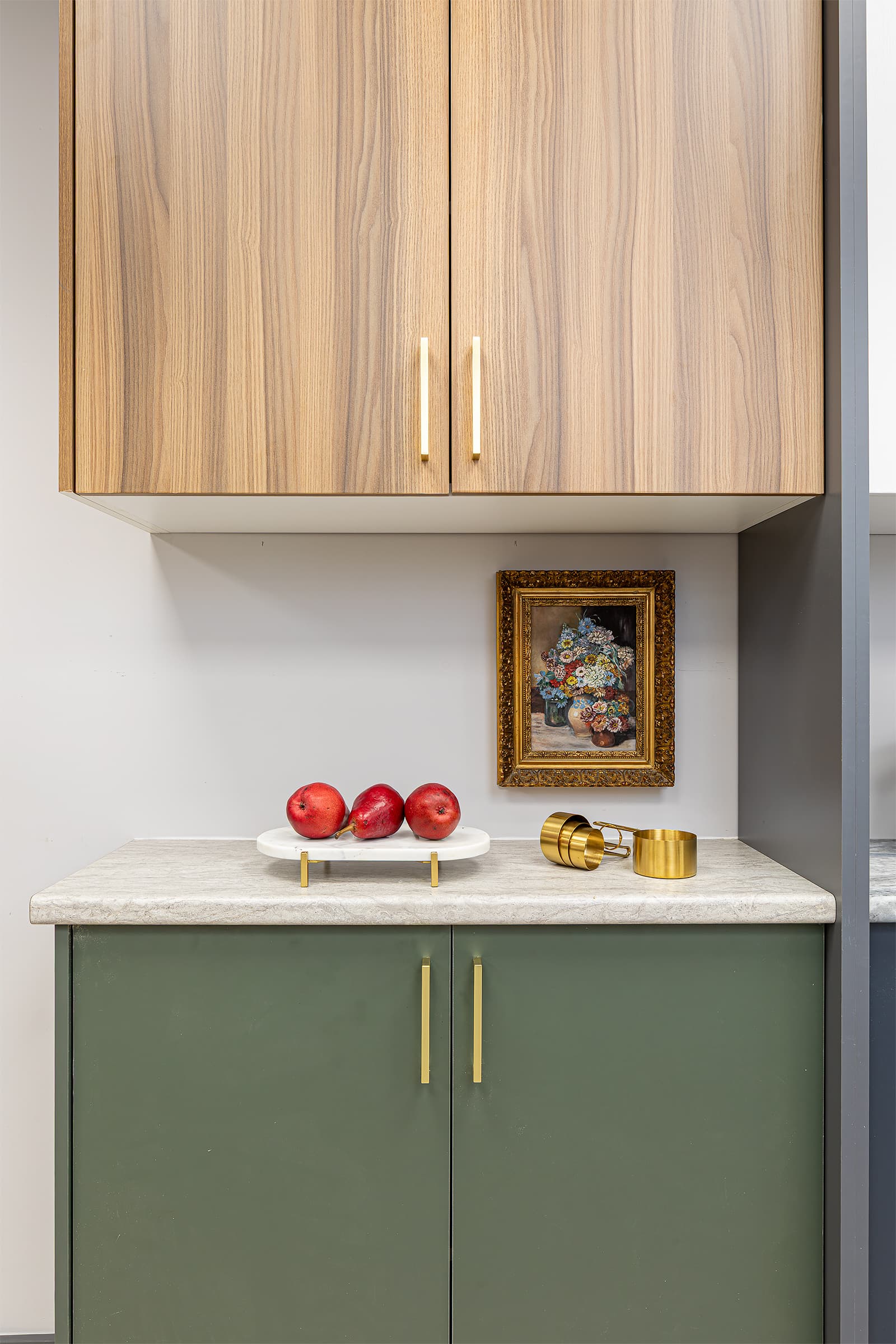 cabinet door and countertop display red pears on marble trivet and brass measuring cups
